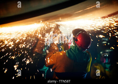 Vista posteriore del lavoratore la saldatura ala di aeroplano presso l'industria Foto Stock