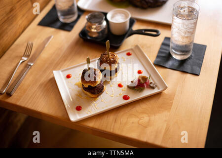 Angolo di Alta Vista del cibo servito nel vassoio con drink sul tavolo di legno nel ristorante Foto Stock