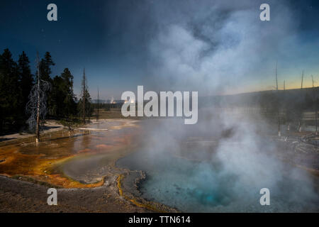 Emissione di vapore da geyser contro il cielo al tramonto Foto Stock