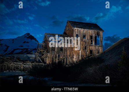 Vecchio abbandonato casa in legno contro il cielo al tramonto Foto Stock