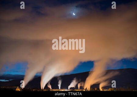 Basso angolo di visualizzazione ad emissione di fumo provenienti dal settore industriale al crepuscolo Foto Stock