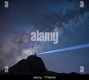 Basso angolo di visione di un escursionista con torcia accesa contro il cielo stellato Foto Stock