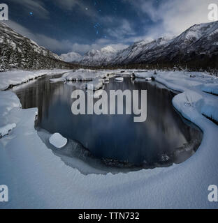 Vista panoramica del lago contro montagne dalle vette innevate a Chugach State Park durante la notte Foto Stock