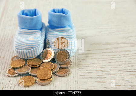 Spese di Parenting concetto. Baby stivaletti e pila di monete Foto Stock