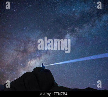 Silhouette escursionista con torcia seduti sulla montagna contro star campo a Joshua Tree National Park Foto Stock