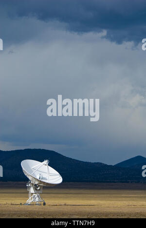 Parabola satellitare sul campo contro il cielo nuvoloso al tramonto Foto Stock