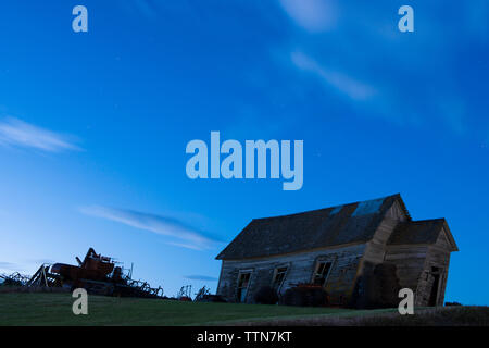 Basso angolo vista della casa abbandonata sul campo contro il cielo blu di notte Foto Stock