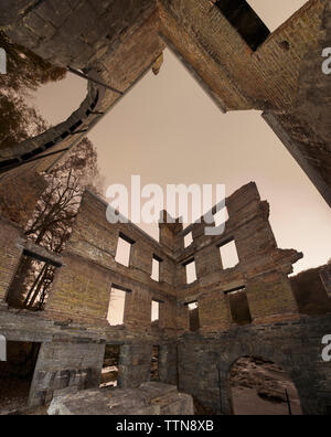 Basso angolo di vista abbandonata danneggiato mulino a Sweetwater Creek parco dello Stato contro il cielo chiaro Foto Stock