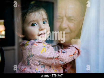 Ritratto di carino nipote portato dal nonno visto attraverso la finestra Foto Stock