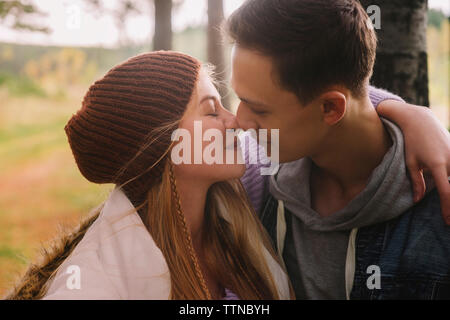 Close-up romantica di coppia giovane kissing mentre è seduto nella foresta Foto Stock