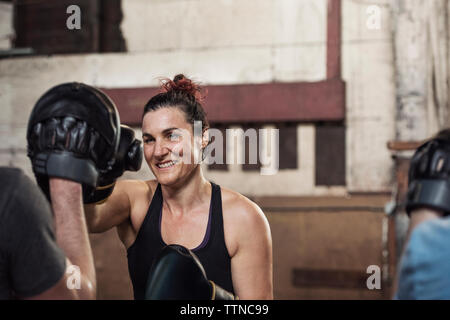 Felice boxer femmina praticando con maschio amico in palestra Foto Stock