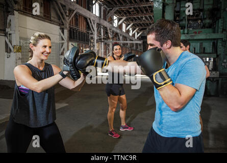 Felice boxer femmina praticare con un amico in un club salute Foto Stock