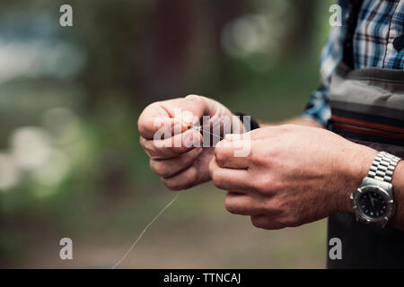 Sezione mediana di uomo maturo holding filo da pesca all'aperto Foto Stock