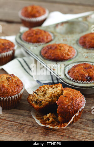 Vista ad alta angolazione di muffin in crusca con vassoio da forno su tavolo di legno a casa Foto Stock