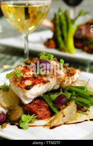 Primo piano del cibo servito in piatto con vino a tavola a casa Foto Stock