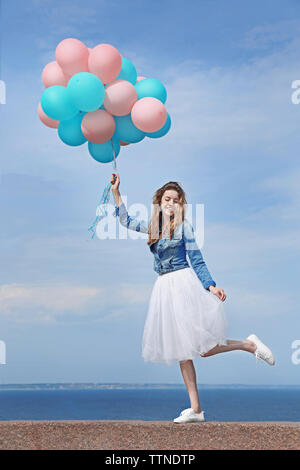 Bella giovane donna con palloncini colorati sul fronte mare Foto Stock