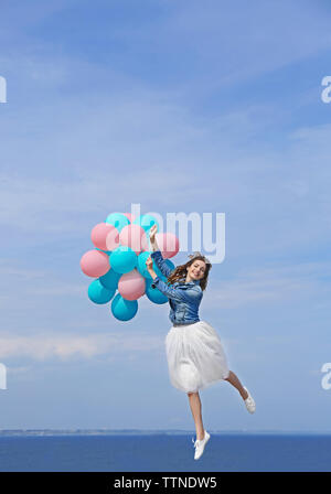 Bella giovane donna con palloncini colorati sul fronte mare Foto Stock