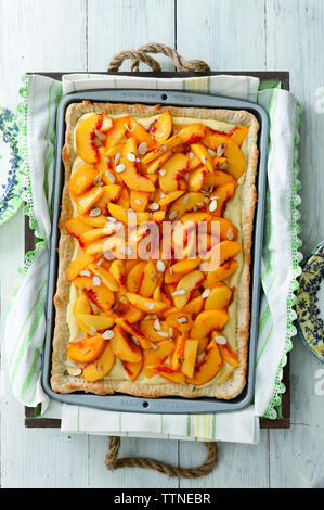 Vista dall'alto delle fette di pesca e mandorle sul cibo dolce in una teglia a casa Foto Stock