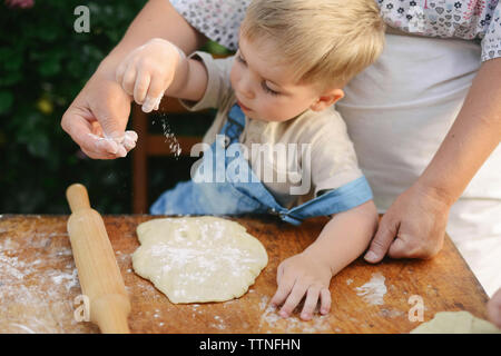 Sezione mediana della madre con figlio preparare del cibo su un tavolo di legno in cantiere Foto Stock