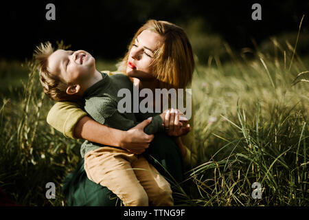 Giovane madre abbraccia il suo piccolo figlio piuttosto all'aperto Foto Stock
