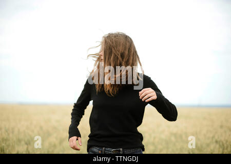 Giovane donna si trova in un campo di grano in estate Foto Stock