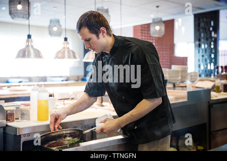 Lo chef maschio di preparare il cibo in cucina commerciale Foto Stock