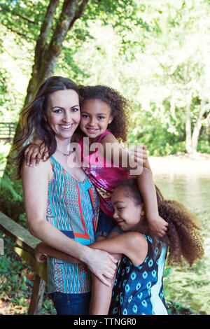 Donna affettuosa con le figlie in piedi sul lungolago Foto Stock