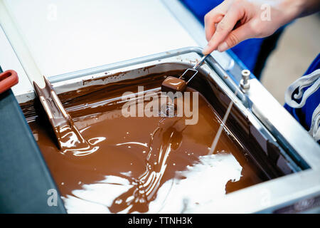 Tagliato a mano femminile di immersione dello chef cioccolato con forcella in fonduta Foto Stock