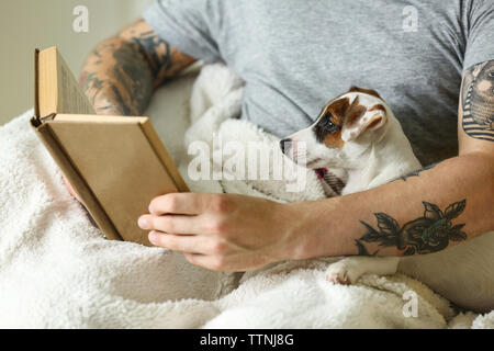 Uomo con cute cane libro di lettura Foto Stock