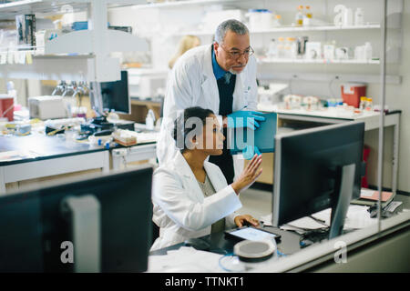 Medico donna discutendo con connettore maschio di tipo medico in sala medica visto attraverso il vetro Foto Stock