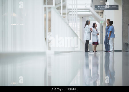 Medici di sesso femminile a discutere mentre in piedi nel corridoio di ospedale Foto Stock