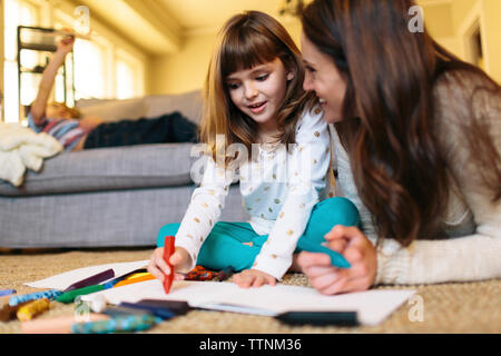 Madre guardando ragazza disegno sulla carta Foto Stock