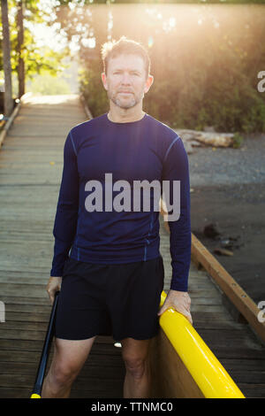 Ritratto di uomo con paddleboard in piedi sul Boardwalk Foto Stock