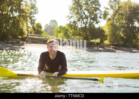 Ritratto di uomo sorridente paddleboarding sul fiume Foto Stock