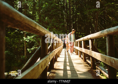 Amici camminando sulla passerella in foresta Foto Stock
