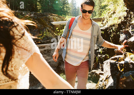 Ritagliate la mano della donna con escursioni amico maschio in foresta Foto Stock