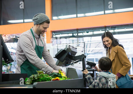 lavoratore che paga mentre si trova al banco del supermercato con il cliente Foto Stock