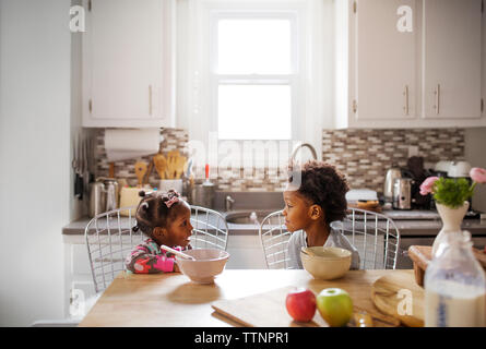 Fratello e Sorella di parlare mentre si consuma la colazione nella cucina Foto Stock