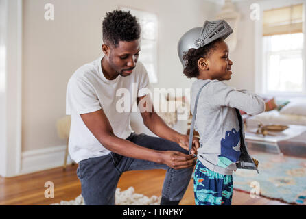 Padre vestire il ragazzo come cavaliere in costume di armor a casa Foto Stock