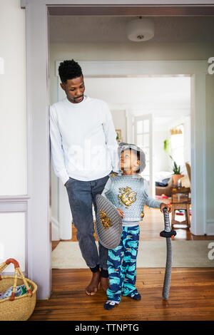 Ragazzo vestito in costume di armor guardando al padre Foto Stock