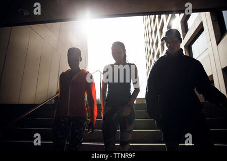 Basso angolo di visione degli atleti correndo giù per passi in metropolitana Foto Stock
