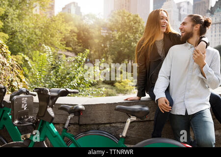 Coppia felice guardando ogni altro mentre appoggiata sulla parete di ritegno Foto Stock