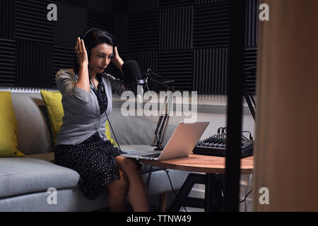 donna d'affari che regola le cuffie durante le videoconferenze in ufficio Foto Stock
