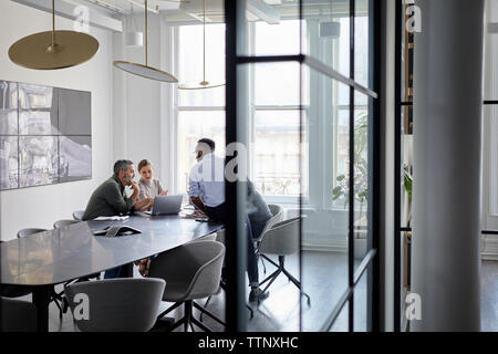 persone in viaggio d'affari che discutono con un computer portatile nella sala conferenze Foto Stock