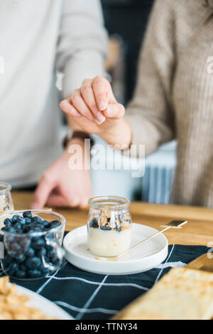 Sezione mediana del giovane in piedi dal cibo a tavola Foto Stock