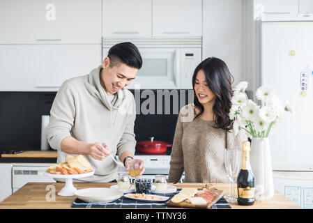 Donna che guarda il ragazzo prepara la colazione in cucina Foto Stock