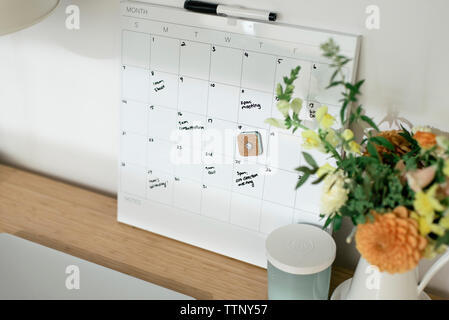 Angolo di alta vista del calendario con testo di vaso di fiori sulla scrivania in ufficio Foto Stock
