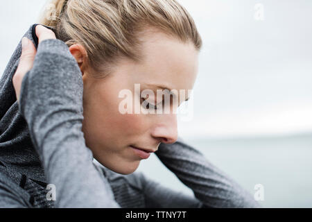 Close-up di bella donna atletica indossando giacca con cappuccio contro il cielo chiaro Foto Stock