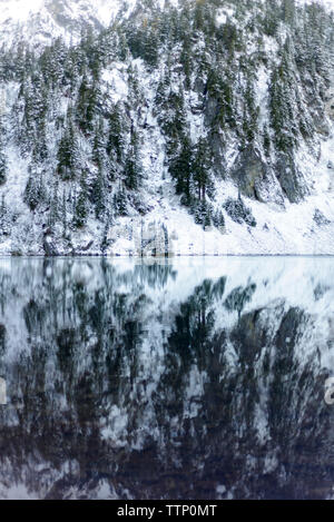 Vista panoramica del lago calmo contro gli alberi innevati nella foresta Foto Stock