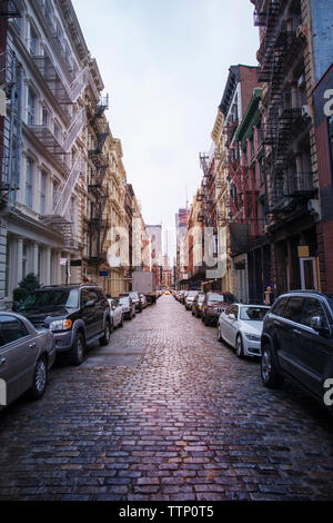 Auto parcheggiata su strada in mezzo a edifici contro il cielo chiaro Foto Stock